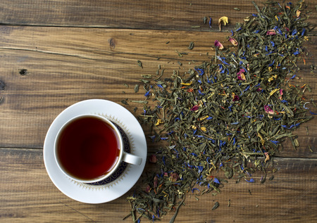 Cup of black tea and herbs on the background of wooden boardsの写真素材