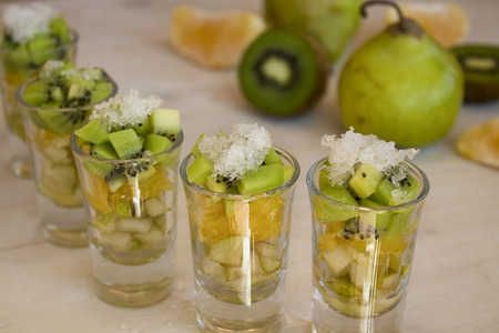 fruit, kiwi, orange and pear in small cups on a light backgroundの写真素材