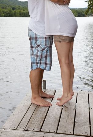 Young couple hugging on a dock at a lake.  Girl is on tip-toe.  Heads not visible.の写真素材