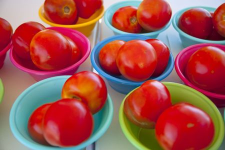 Red tomatoes in colorful plastic bowlsの写真素材