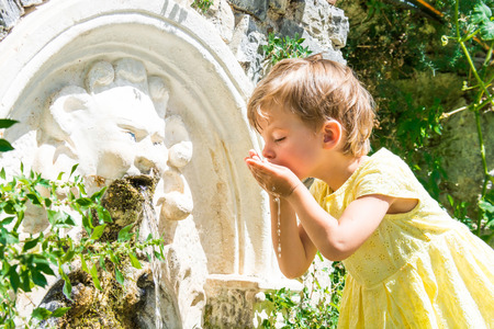Little girl washes in a source in green bushes.の写真素材