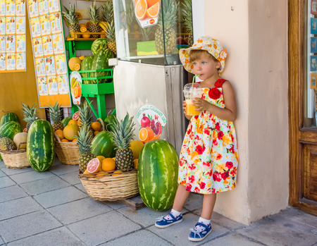 Girl with a glass of juice on the street outside the shop.の写真素材