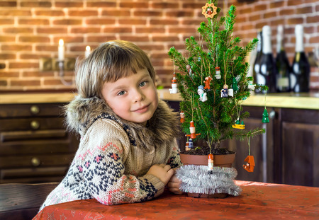 New Year's Eve. Girl sitting near a small Christmas tree.の写真素材