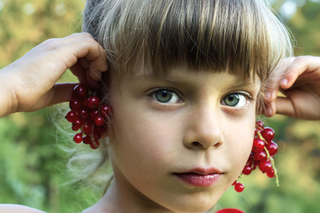 Beauty girl tries on earrings from red currant berries.の写真素材