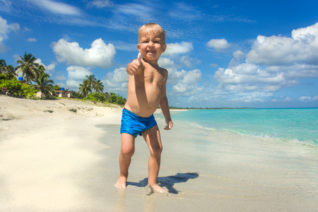 Cute little boy walking on the beach on the daytimeの写真素材