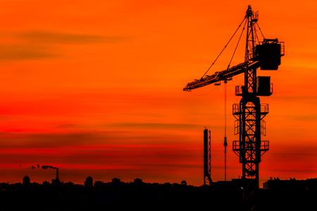 Silhouette of building crane on the sunset.の写真素材