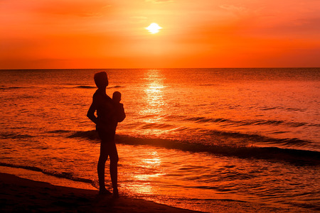 Mother with newborn at sunset on the beach.の写真素材