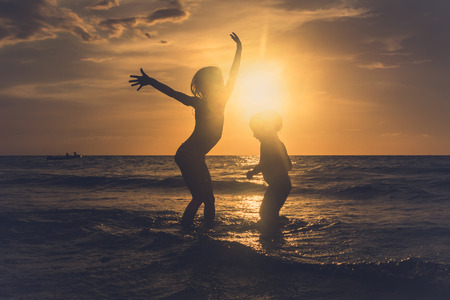 Funny kids dancing on the tropical beach at sunset.の写真素材