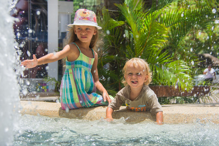 Two children playing in fountain splashes on hot summer day.の写真素材