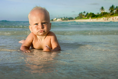 Cute infant lying in the water of a tropical beach.の写真素材