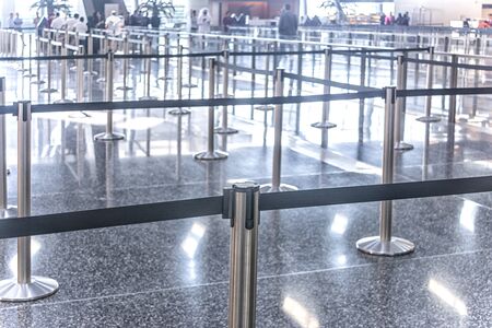 The public check-in area of a modern airport with crowd control barriersの写真素材