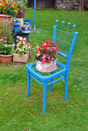 Blue chairs and flower pot of red flowers.の写真素材