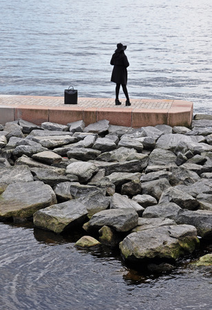 A woman is standing on a pier and waiting for a boat.の写真素材