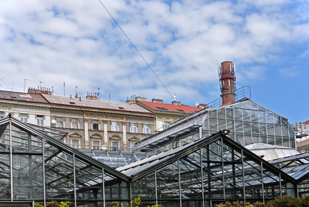 Greenhouses made of steel construction with old residential buildings and a chimney in the backgroundの写真素材