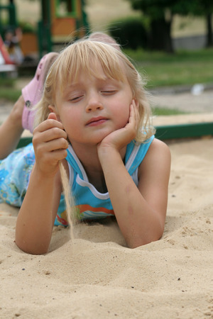 Little girl playing in the sandbox on a summer dayの写真素材