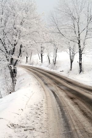 Slippery winter road with a turning among tree and mountainsの写真素材