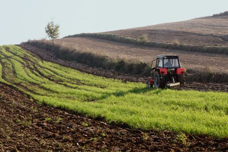 Red - black tractor working on a fieldの写真素材
