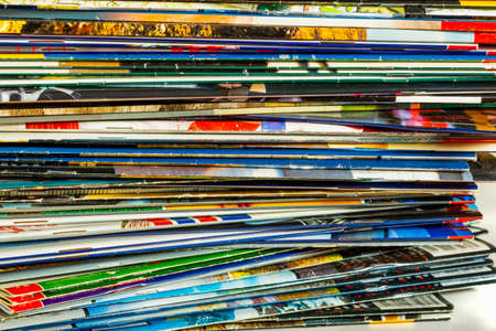 A messy pile of old, colorful magazines on light background.の写真素材