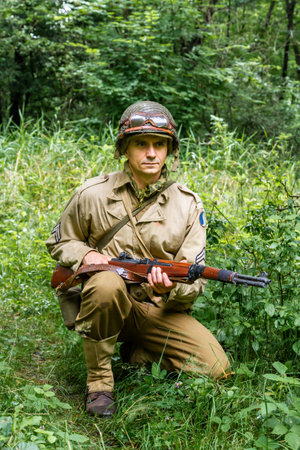 Historical reeneactor dressed as american infantry soldier during World War II patrol the forest. Porabka, Polandの写真素材
