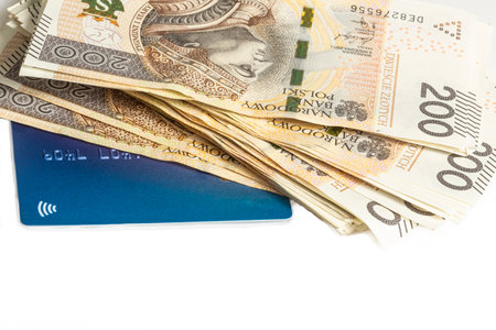 A large stack of Polish 200 zloty banknotes and blue credit card on a white background. Synonymous with wealth and abundance.の写真素材