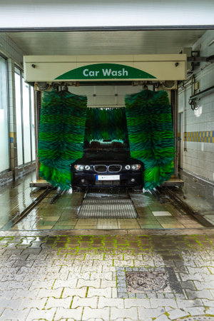 An automatic car wash with a passenger car in the process of getting washed.の写真素材