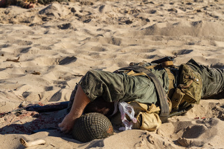 Historical reconstruction. Injured or dead World War II infantry soldier on the beach. View from the...