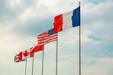 Flags France, USA Polish, Canada and Great Britain blow in the wind against a blue sky. D Day Hel,...