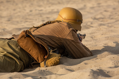 Historical reconstruction of a desert battle. A soldier in combat position on sandy terrain. View...