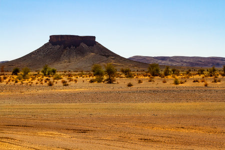 Dry stone desert and lonely table mountain in the background. Moroccoの写真素材