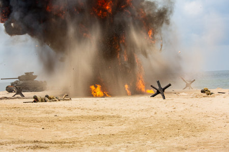 World War II historical reconstruction. Battlefield. Explosions, a tank, and American soldiers on...
