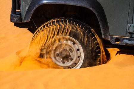 Close-up. Background. The wheel of a car digging in deep sand. Capturing the movement and energy while driving off-road.の写真素材