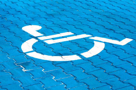 Background. White sign for disabled parking on blue cobblestones. Polandの写真素材