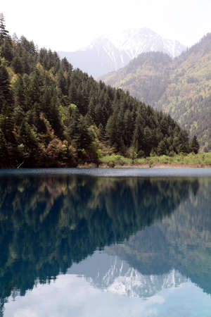Portrait view of the hills and valley clearly reflected in the bright blue lakeの写真素材