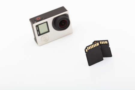 Two Black SD Memory Cards And Blurry Action Camera on a White Background