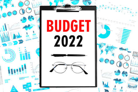 Text BUDGET 2022 on clipboard. Pen and glasses on clipboard with charts, documents and graphs. Business concept top view.の写真素材