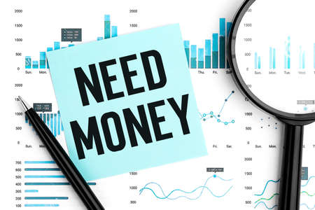 Word NEED MONEY on sticker. Magnifier, pen and charts and graphs top view. Business and statistical concept on white background.の写真素材