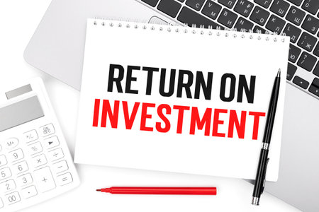 Text ROI - RETURN ON INVESTMENT on notebook, laptop, calculator, pen on white background.の写真素材