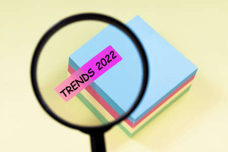 Close up magnifier with text TRENDS 2022 on pink sticker on yellow backgroundの写真素材