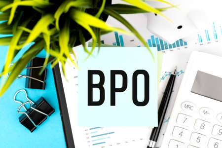 Text BPO Business Process Outsourcing on blue sticker, magnifier, pen, graphs. Business flat lay.の写真素材