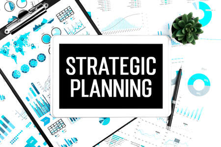 Text STRATEGIC PLANNING on tablet. Pen, clipboard and graphs. Business concept. Flat lay.の写真素材