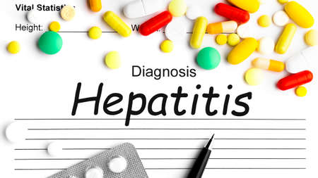 Word HEPATITIS on paper with pen, assorted pharmaceutical medicine pills, tablets and capsulesの写真素材