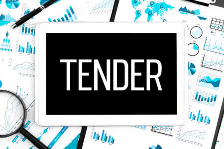 Word TENDER on tablet, clipboard, magnifier, chart, diagram and pen on office desk. Business concept.の写真素材