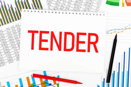 Word TENDER on notebook, pen, marker, chart, diagram on office desk. Close up. Business concept.の写真素材