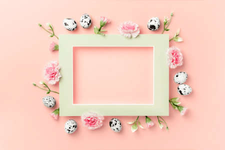 Happy Easter concept. Frame of Easter eggs and spring flowers on pink paper background. Flat lay,...