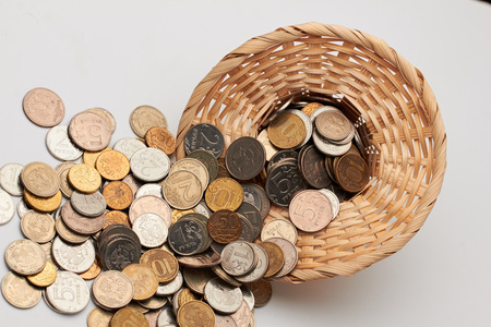 Wicker hat with coins on white background.