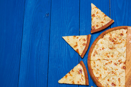 Pizza with three cheeses on a wooden board blue.の写真素材