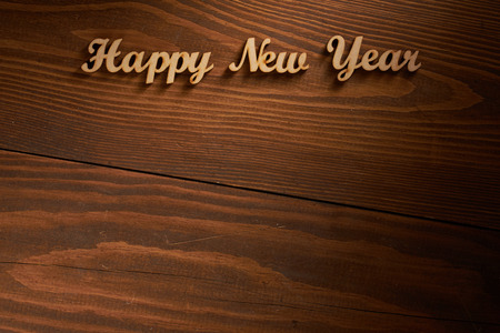 Happy New Year! - A phrase with wooden letters on a wooden background.