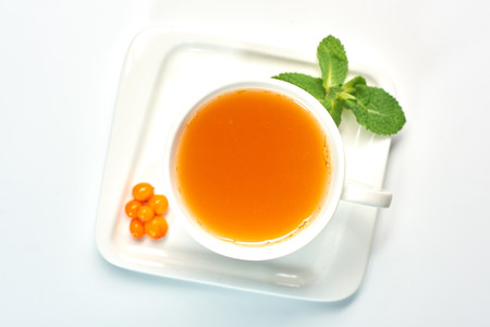 Cup of tea with sea buckthorn. Porcelain cup with sea buckthorn tea on white background.の写真素材