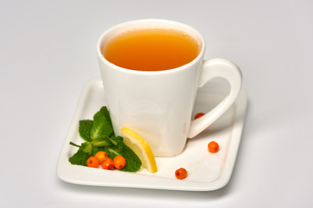 Cup of tea with sea buckthorn./Porcelain cup with sea buckthorn tea on white background.の写真素材