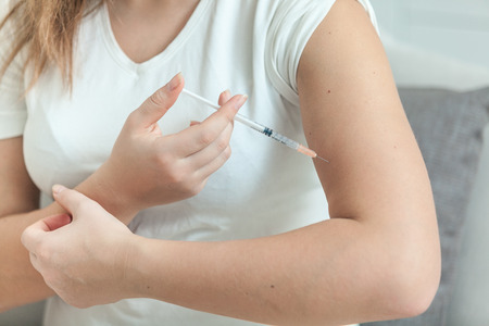woman doing injection with syringe in handの写真素材